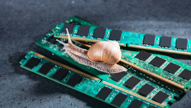 istock Snail on the slats of RAM. Old obsolete memory. Slow RAM. Computer components. Dark background. 1387469458
