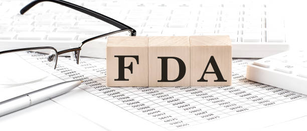 istock FDA written on wooden cube with keyboard , calculator, chart,glasses.Business concept 1387472103