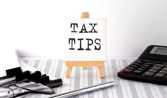 text TAX TIPS on the easel with office tools and paper.Top view. Business concept