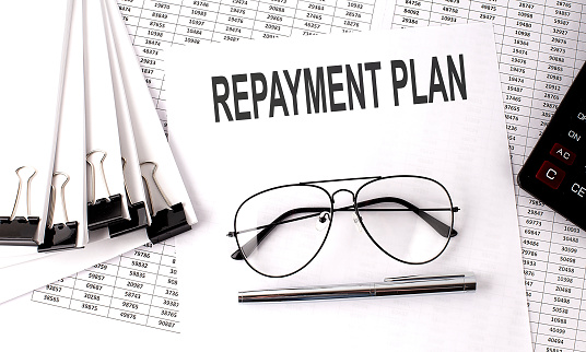 REPAYMENT PLAN text on the paper with chart and office tools , business concept