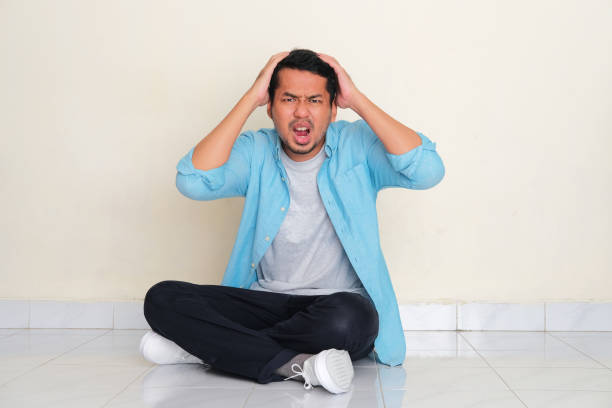 full body portrait of adult asian man sitting cross legged showing stressed gesture - pusing imagens e fotografias de stock