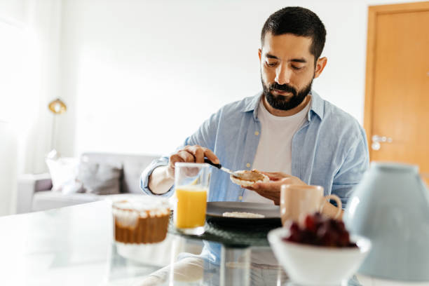 man sitting at the table eating vegan breakfast - lanche da tarde imagens e fotografias de stock