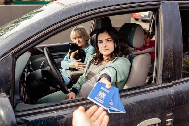 familia en coche dando pasaportes ucranianos para el control aduanero cruzando la frontera a europa mientras huye de ucrania debido a la invasión rusa. texto en los pasaportes: pasaporte de ucrania - border control fotos fotografías e imágenes de stock