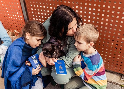 Madre con niños y gatos con pasaportes que huyen de Ucrania esperando ayuda y registro en un centro de caridad. El texto en los pasaportes es: Pasaporte de Ucrania photo