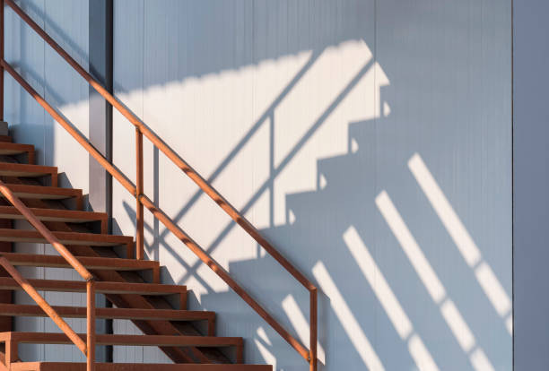 istock Sunlight and shadow on surface of the old metal staircase on gray sandwich panel wall outside of cold storage 1387478241