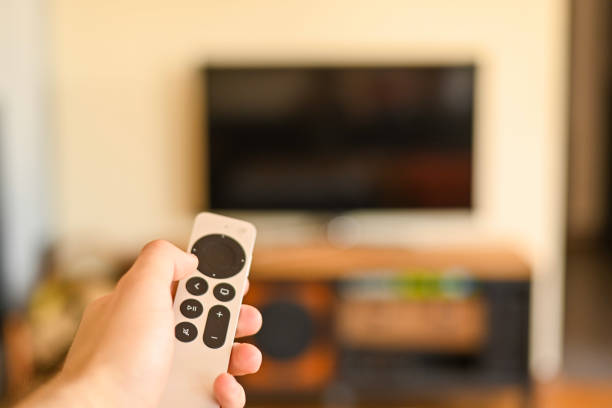 istock Hand with tv remote control switching television on at home. smart tv. selective focus 1387478263