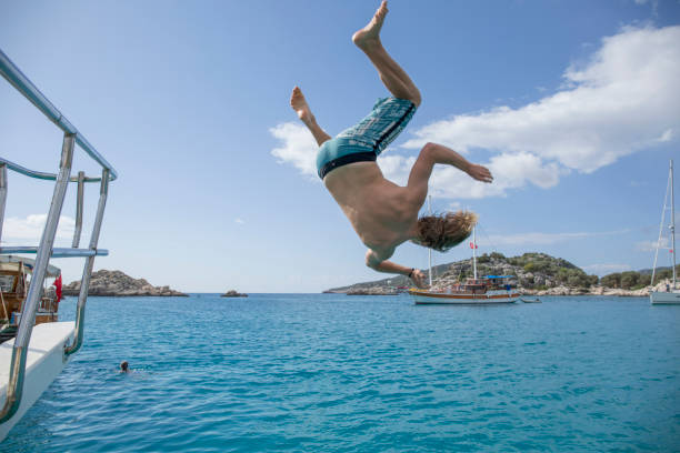 istock Young man jump mid-air above sea 1387485069