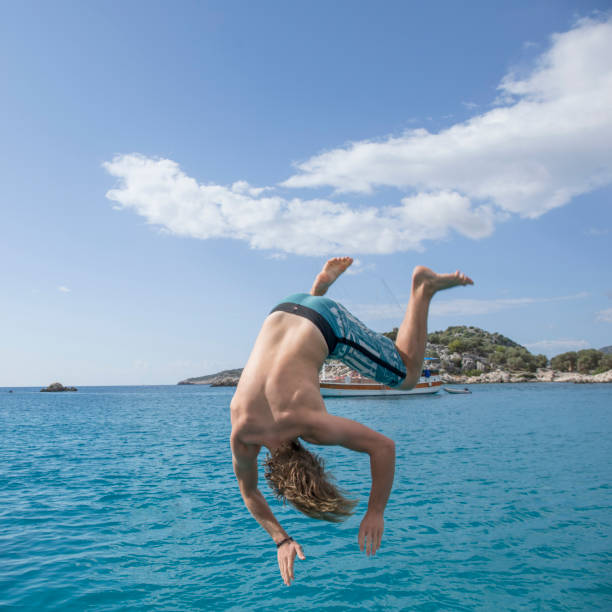 istock Young man jump mid-air above sea 1387485095