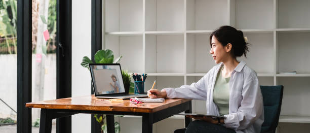 istock Cropped photo of woman writing making list taking notes in notepad working or learning on laptop indoors- educational course or training, seminar, education online concept 1387485767