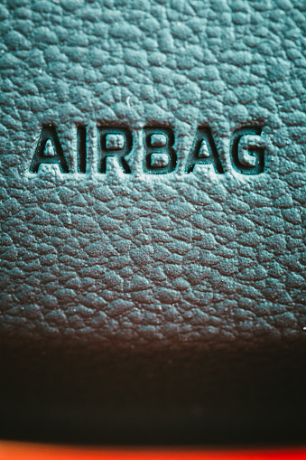 Extreme close up color image depicting the word 'airbag' on the textured steering wheel of a car. Lots of room for copy space.