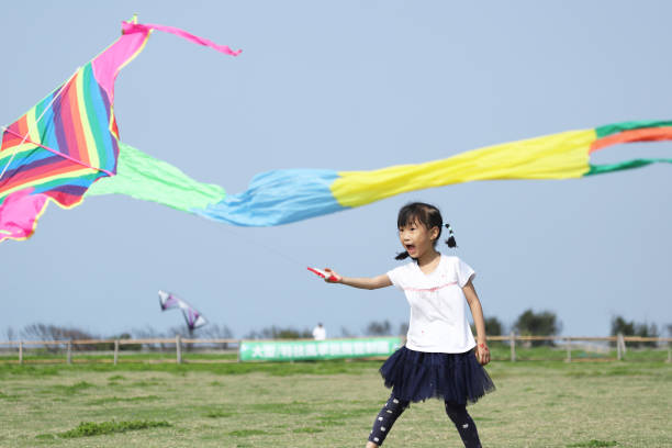 istock asian girls playing and flying kite in a meadow. 1387486607