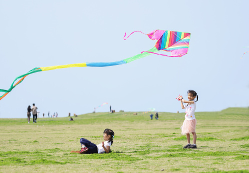 Young father with his sons fly a kite together near the sea on sunset. Father’s Day