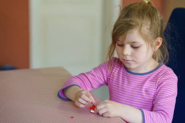 istock Little creative toddler girl playing with small plastic blocks. Active child having fun with creating. Education for kids. Fun activity. 1387486952
