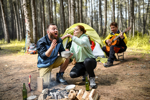 Male Getting Tongue Burned By Hot Stew While Camping With Friends In Forest
