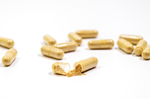 Capsules with bio additives. Tablets and capsules as a treatment of a disease. Capsule with natural supplements on white table background. Macro with Selective focus