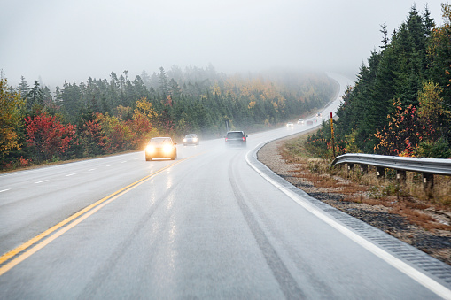Car driver's point of view driving up a winding, wet, slippery uphill grade on a Canadian highway on a trip to Peggy's Cove in Nova Scotia, Canada during a foggy mid-October rain storm.
