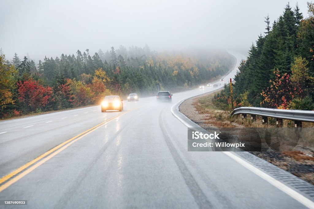 Car Point of View Driving on Winding Wet Canadian Highway Car driver's point of view driving up a winding, wet, slippery uphill grade on a Canadian highway on a trip to Peggy's Cove in Nova Scotia, Canada during a foggy mid-October rain storm. Driving Stock Photo