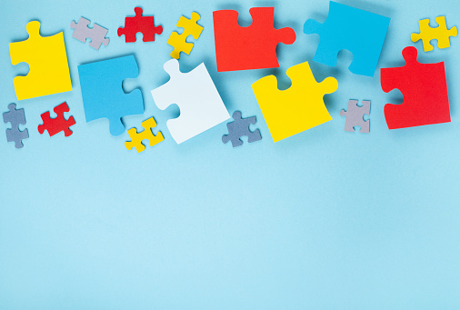 World Autism Awareness Day or month concept. Creative design for April 2. Color puzzle, symbol of awareness for autism spectrum disorder on blue background. Top view, copy space for text.