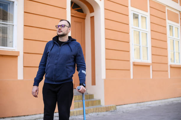 istock Man walking with crutches on the street 1387491790