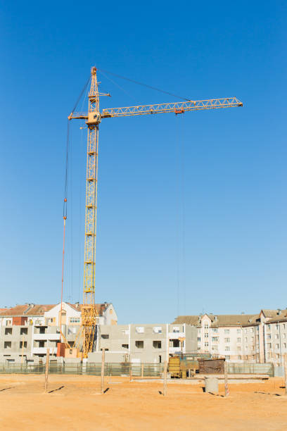 Construction industry. Crane builds a house against blue sky.