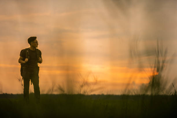 istock Asian Chinese backpacker man standing looking away in paddy field sunset time. 1387493671