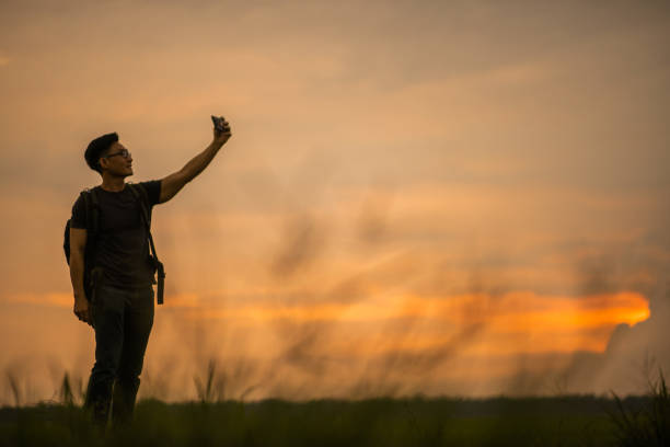 istock Asian Chinese backpacker man taking photo in paddy field sunset time. 1387493679