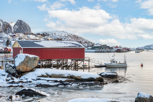 Red rorbuer fishing house with boat on coastline on winter season in Lofoten islands, Norway