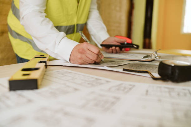 istock unrecognizable architect working on blueprints on construction site. Home improvement, renovation 1387495257