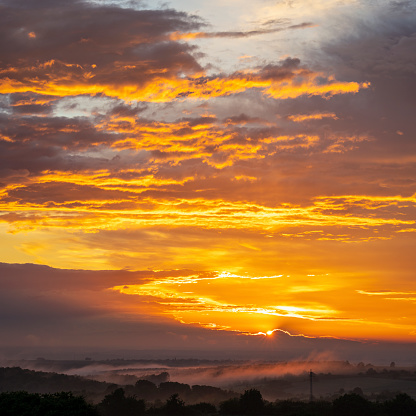 A landscape image of a foggy sunrise.