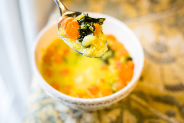 Bowl of coconut lentil soup made with lentil, coconut milk, chopped carrots, kale, onion and garlic with turmeric spice