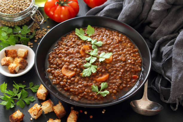 istock Delicious lentils soup served with toaster bread on dark table. 1387500659