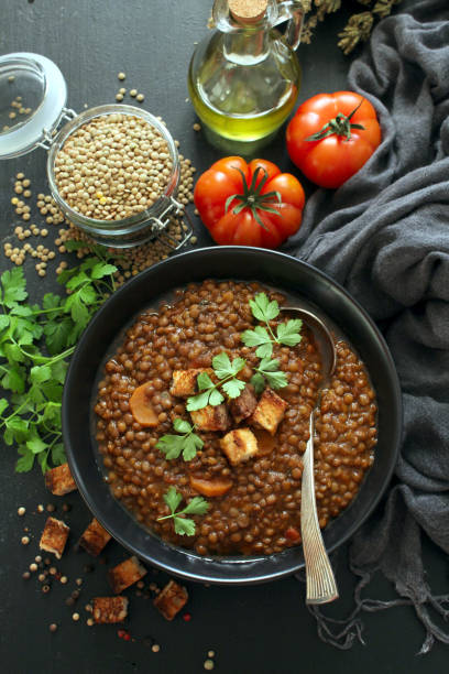 istock Delicious lentils soup served with toaster bread on dark table. 1387500684