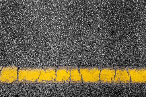 top view of a black dark road street tarmac surface background texture with copy space and yellow line marking