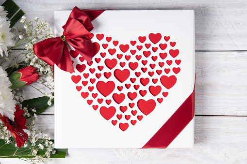 Valentine's day gift, red heart praline box and flower bouquet on white wooden table. High quality photo