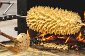 Preparing on an open fire and flames Sakotis, Lithuanian or Polish traditional cuisine layered cake, biscuit or sweet