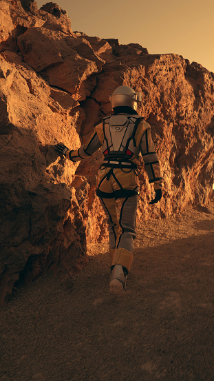 Red dirt on Mars surface. Woman wearing futuristic exoskeleton exploring cave and mountain areas