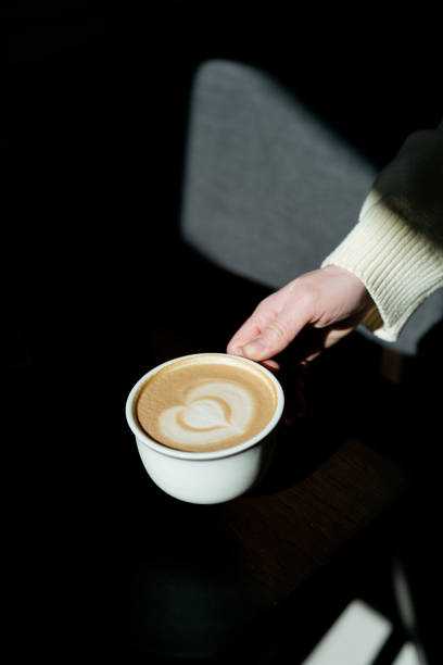 istock Female hand holding cup with coffee at sunny day 1387508986