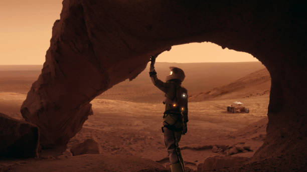 istock Loneliness on Mars. Female astronaut exploring rust colored caves and rocks. Touching stone walls 1387509037
