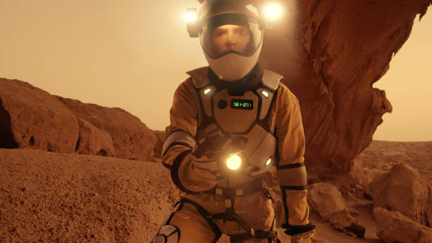 istock Loneliness on Mars. Female astronaut exploring rust colored caves and rocks. Illuminated spacesuit 1387509263