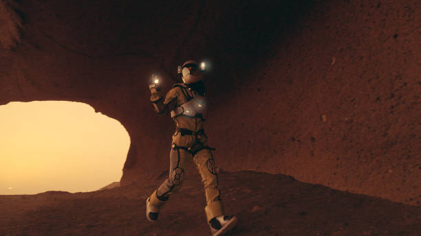 istock Loneliness on Mars. Female astronaut exploring rust colored caves and rocks. Illuminated spacesuit 1387509267