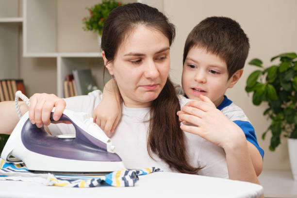 un bambino piccolo di 4 anni impedisce a sua madre di stirare i vestiti. - surprise child 4 5 years little boys foto e immagini stock