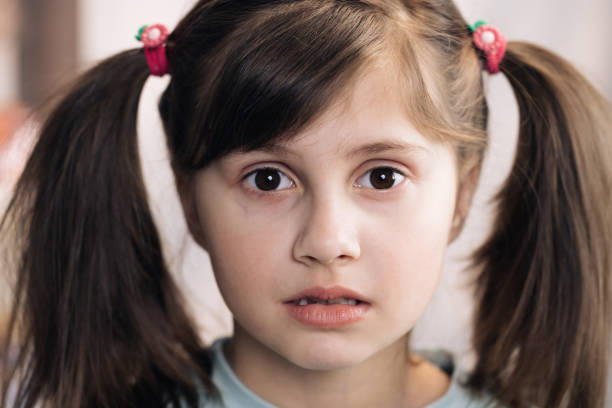 Adorable child with big brown eyes surprisingly react on something, look at camera. Close-up portrait of caucasian black haired girl isolated home. Emotional child