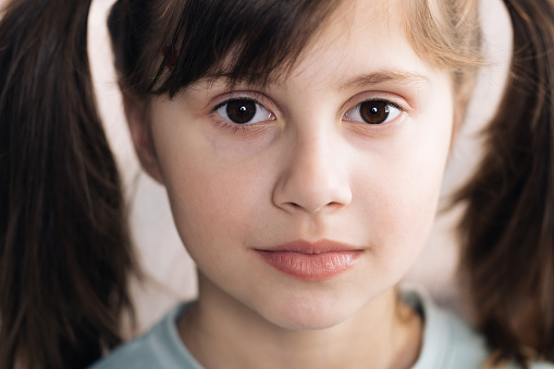 Close-up portrait of caucasian black haired girl isolated home. Adorable child with big brown eyes surprisingly react on something, look at camera. Emotional child