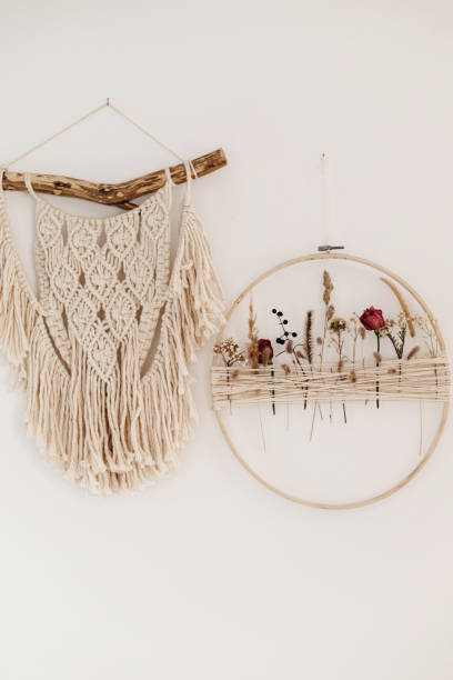 istock Stylish boho wreath with dry flowers and macrame hanging on white wall. Modern floral arrangement and creative handmade decor in modern boho room 1387514029