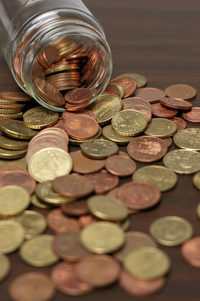 istock Coins spilling from a glass jar 1387514471