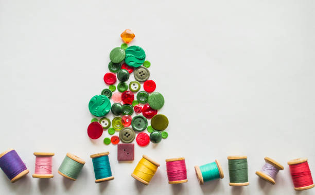 istock Tree made of buttons green, red color. Multicolored threads with wooden spools. White background, copy space. Creative Christmas concept, or gardening 1387515502