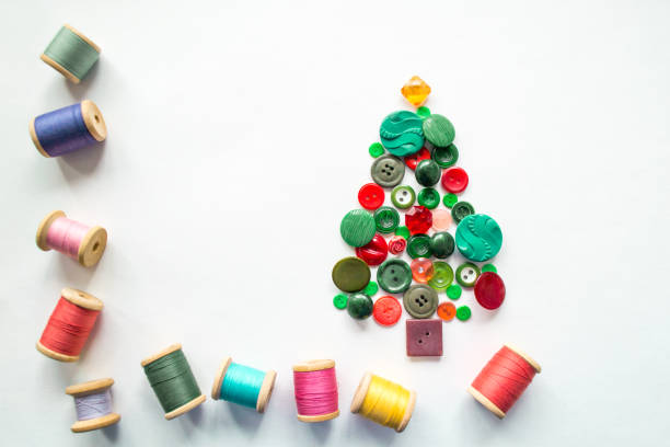 istock Tree made of buttons green, red color. Multicolored threads with wooden spools. White background, copy space. Creative Christmas concept, or gardening 1387515510
