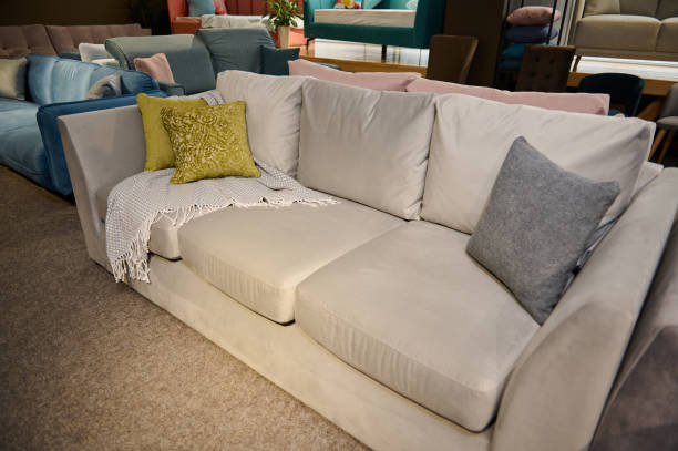 istock Comfortable upholstered settee with colored stylish green olive pillows displayed for sale in the furniture store showroom. Exhibition of upholstered furniture. 1387517643