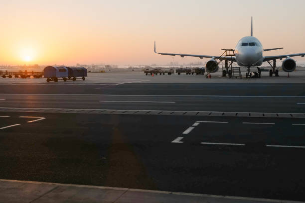 the plane in front of the airport terminal at sunrise - havaalanları stok fotoğraflar ve resimler