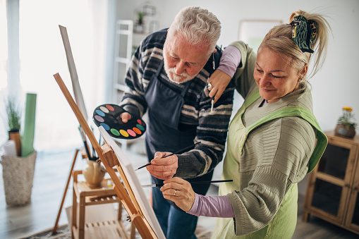 senior couple painting on canvas at home